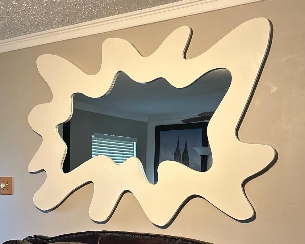 Wall mirror with an irregular, splash-shaped white lacquered frame