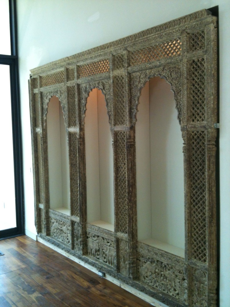 Three arched display niches framed by an intricately carved wood screen built into a wall