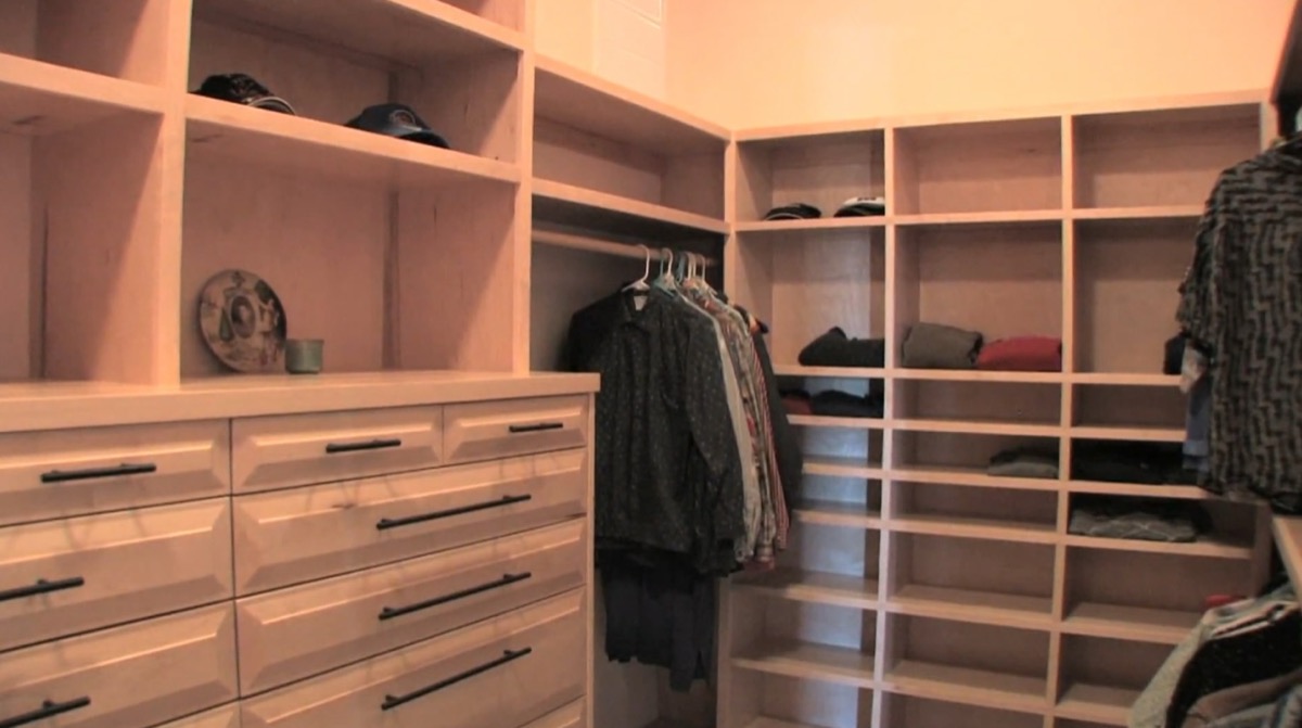 Floor-to-ceiling built-in wardrobe with a bank of drawers, open shelving, and hanging sections in pale plywood